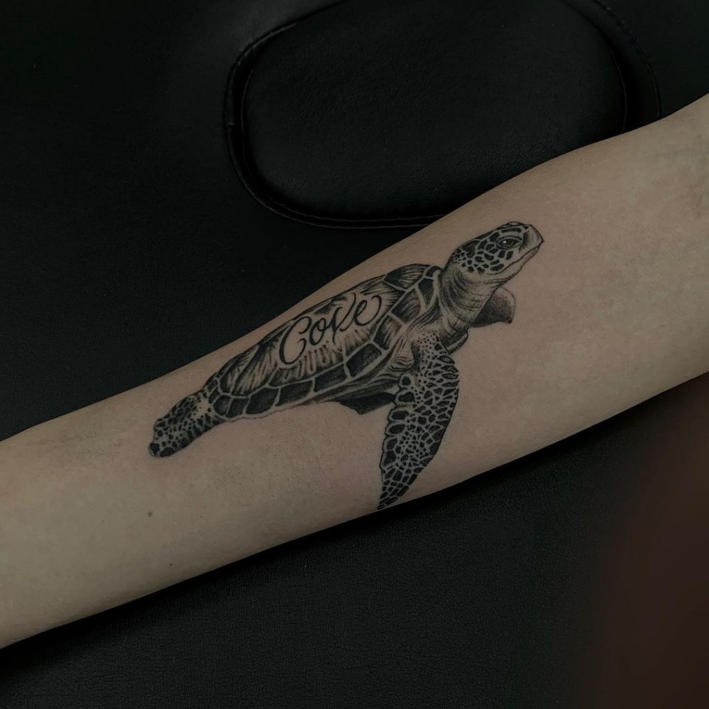 A tiny sea turtle tattoo with the word "love" written at the center of its shell.