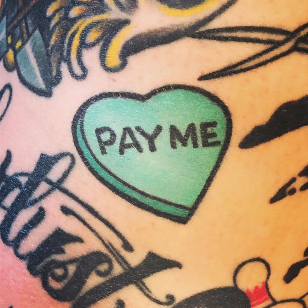 A Pay Me written in a heart tattoo design